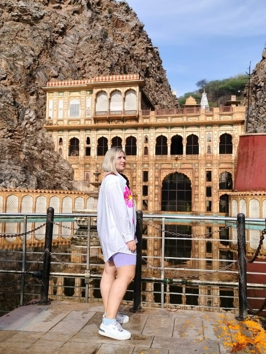 Turista straniero osserva le scimmie nel Tempio di Galta (Monkey Temple) a Jaipur, Rajasthan, durante una visita culturale in India.