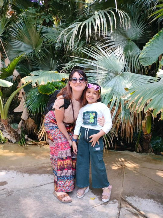 Ragazza italiana con una bambina indiana in un giardino rurale vicino a un recinto di capre in India
