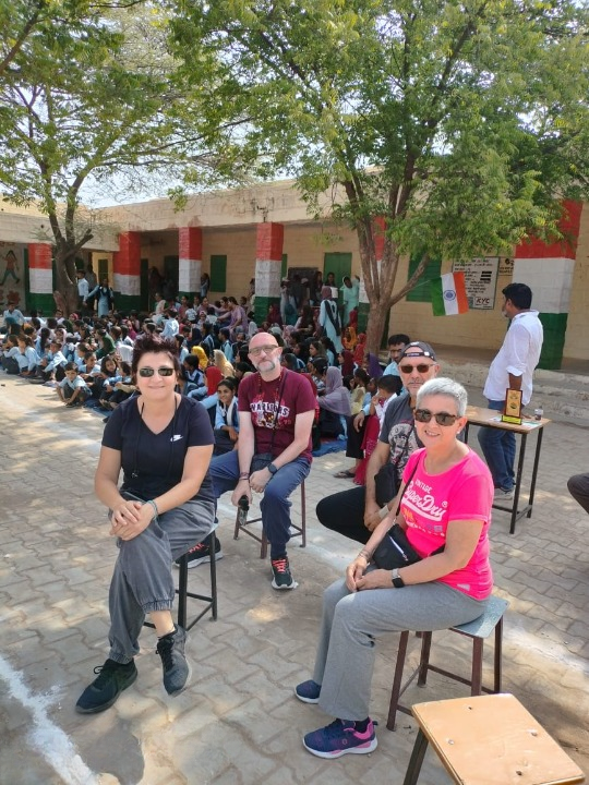 Quattro turisti stranieri visitano una scuola in India insieme agli studenti locali
